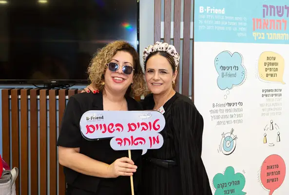 תמונה של רבקה אלקובי יחד עם גננת מחזיקה שלט שעליו כתוב "טובים השניים מן האחד"